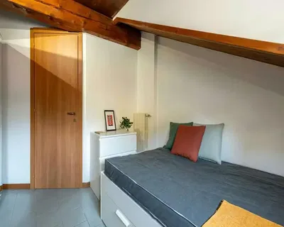 Camera da letto; travi in legno, pavimento in piastrelle, luce naturale